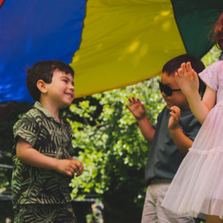 Two toddlers playing under a parachute.