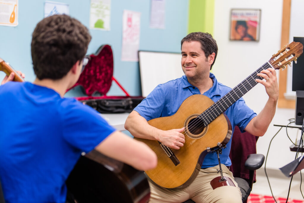 Classical guitar teacher smiling at student