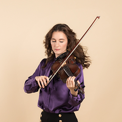 Image of a women in a purple top playing the violin.