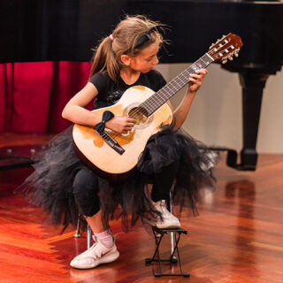 Young female Suzuki guitar student performing