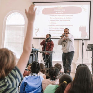 Two musicians leading a workshop for a group of students.
