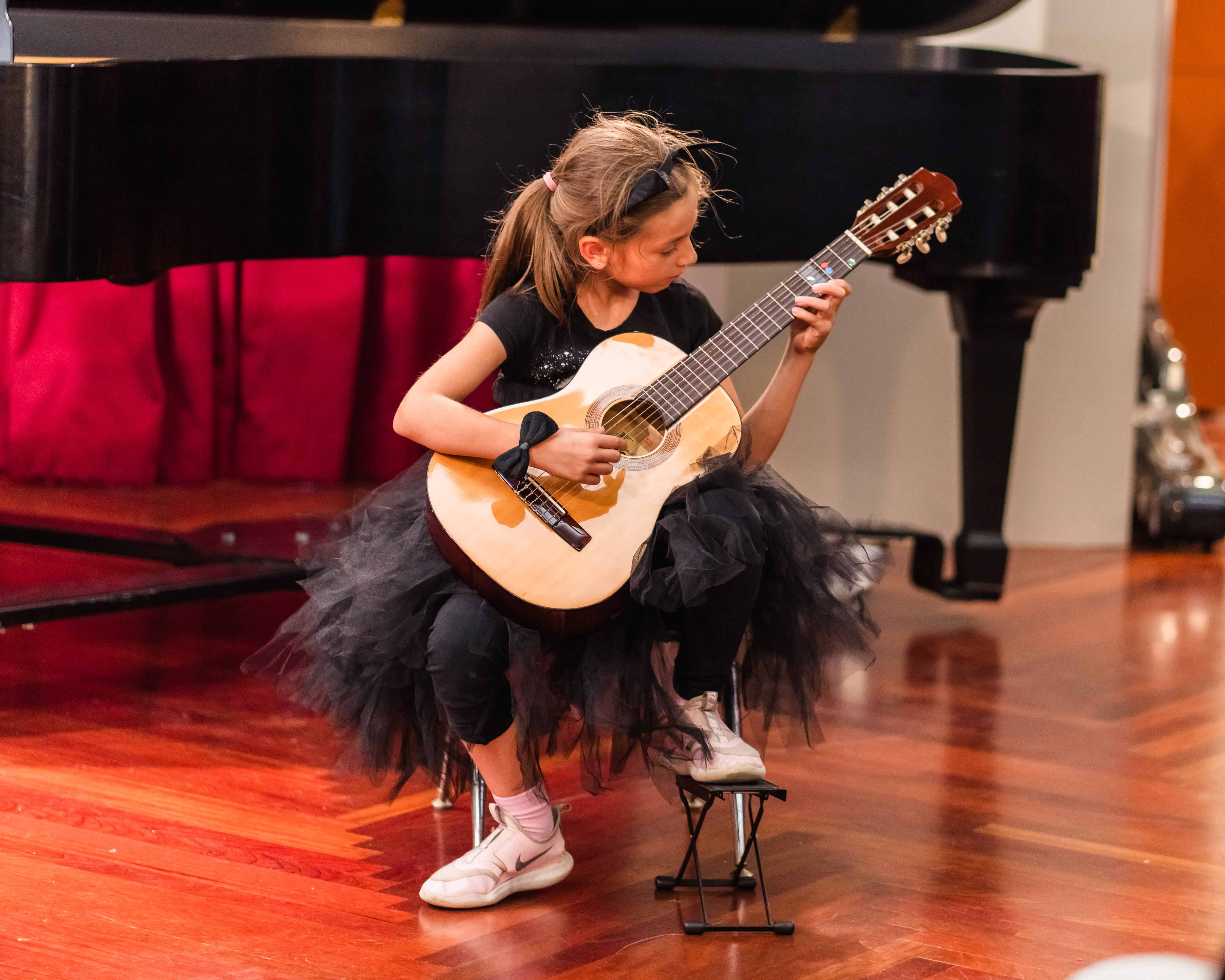Student playing guitar in a recital