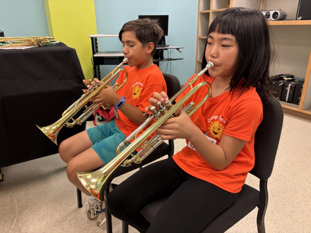 Two campers playing trumpets.