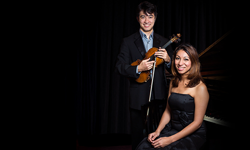 Jamila Tekalli Hanner seated at piano with Suliman Tekalli holding a violin.