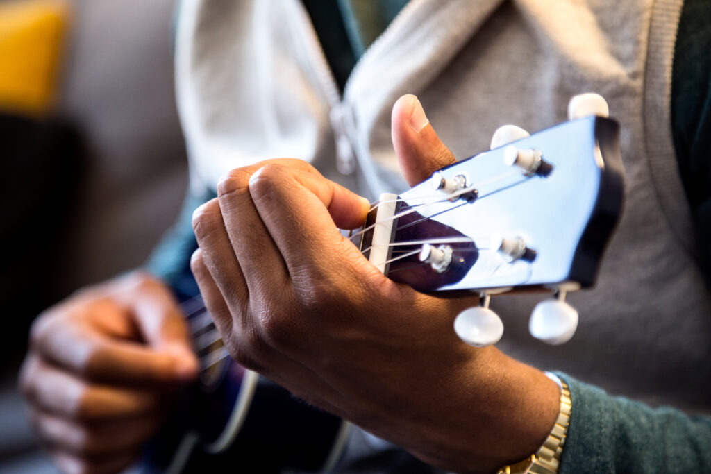 Handsome young black man playing the guitar at home.