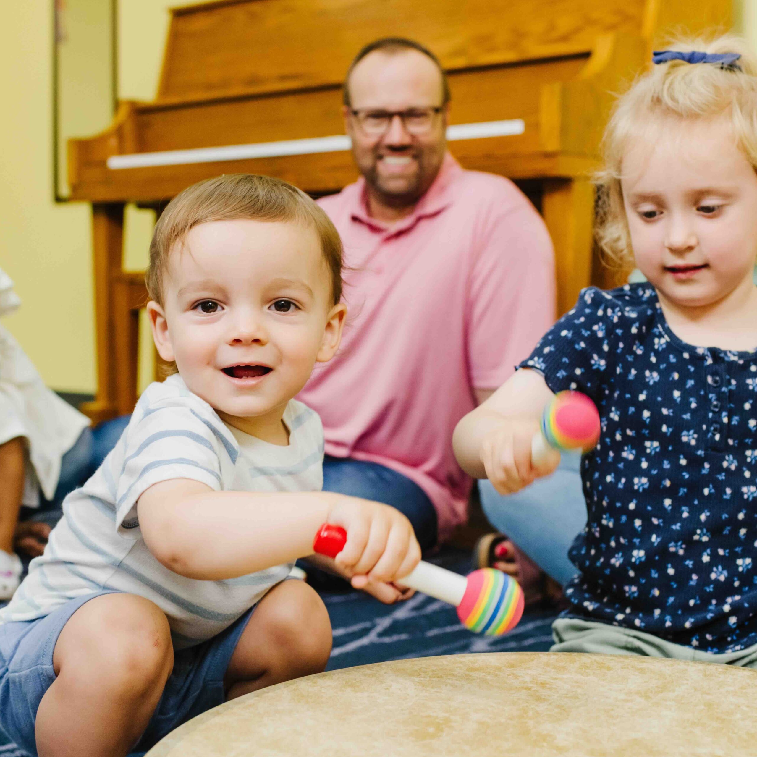 Two students playing a drum in a First Music class.