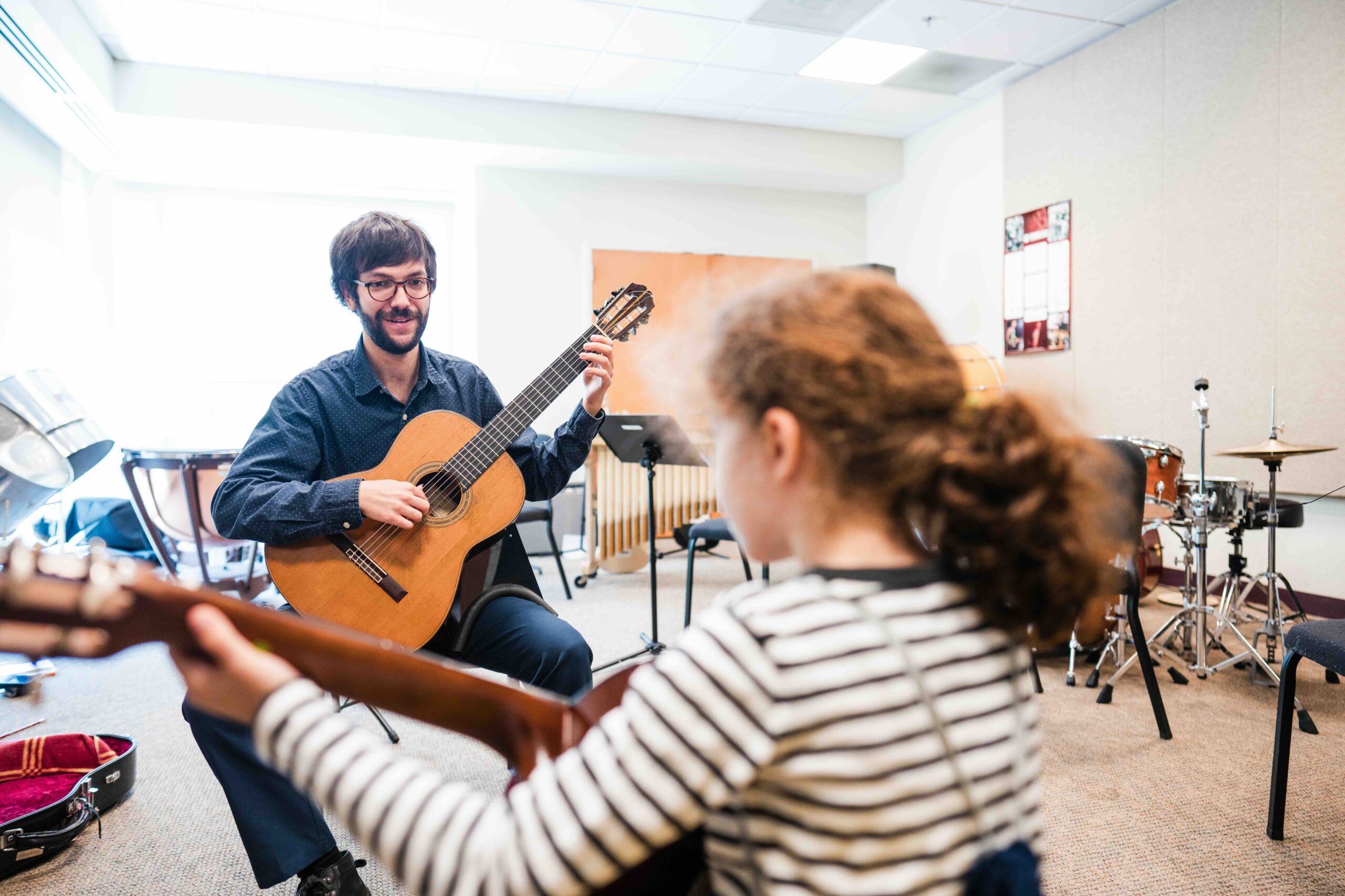 A faculty member leading a guitar lesson at THEARC.