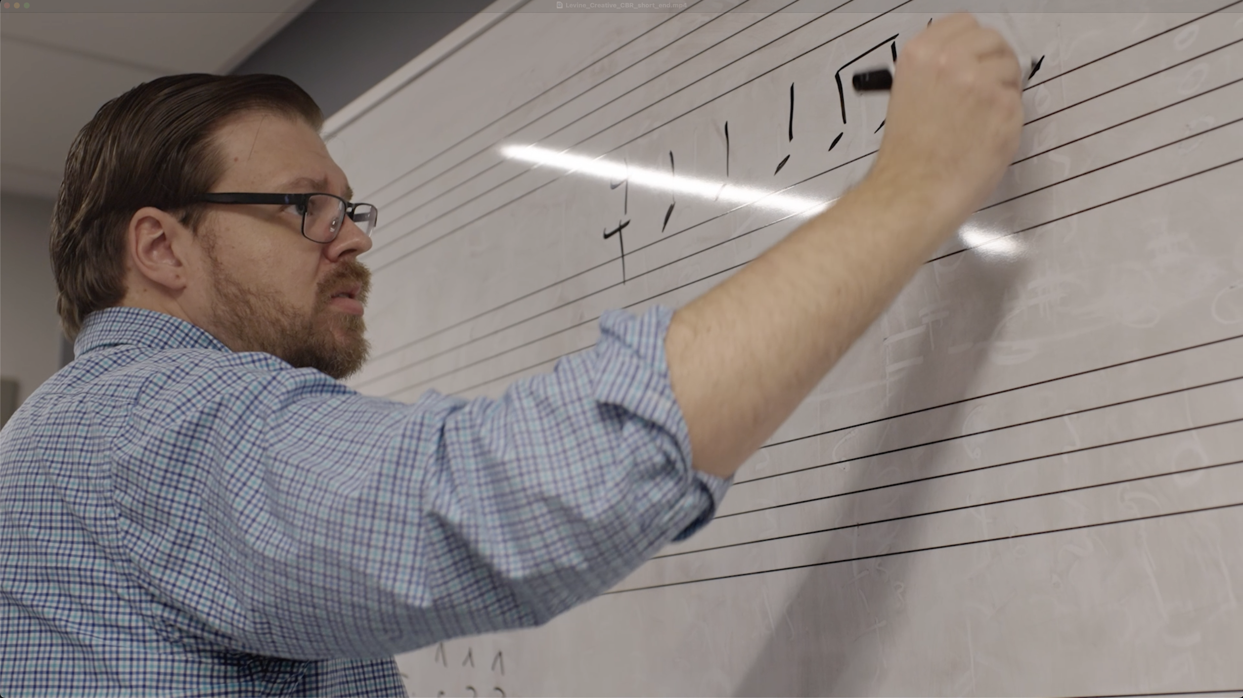 A faculty member writing on a whiteboard.