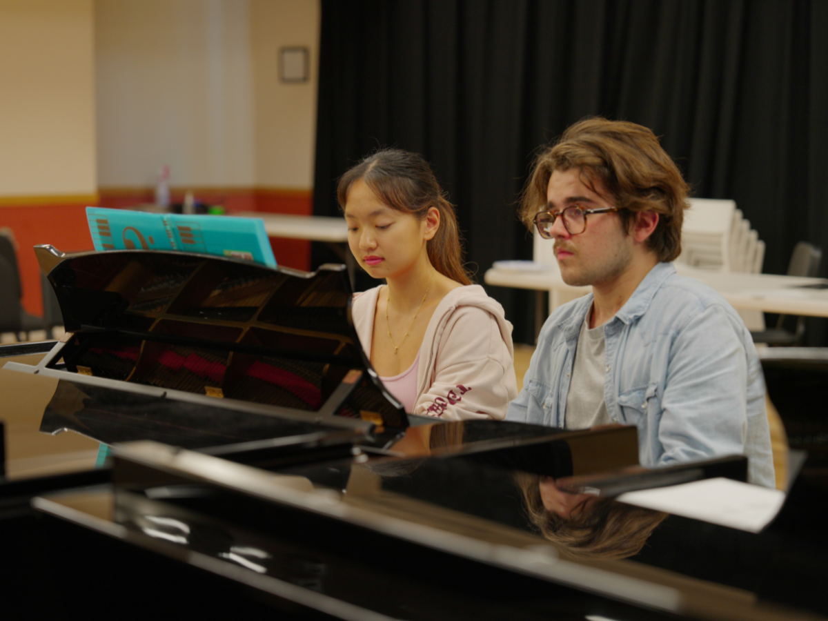 Two teen pianist playing one piano.