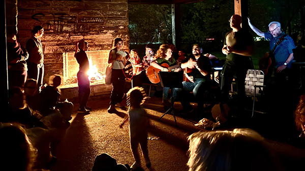Children and adults at a campfire singalong.