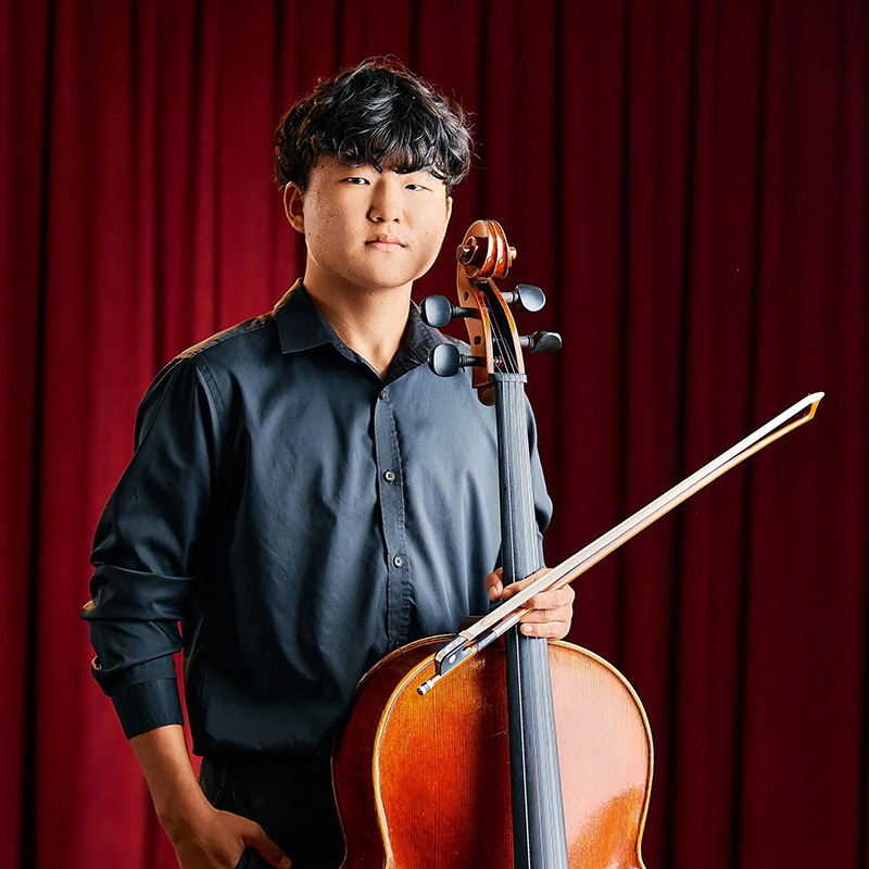 Photo of Andrew Chi holding a cello.