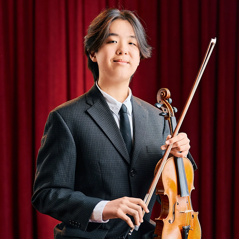 Photo of Bright Wang holding a violin.