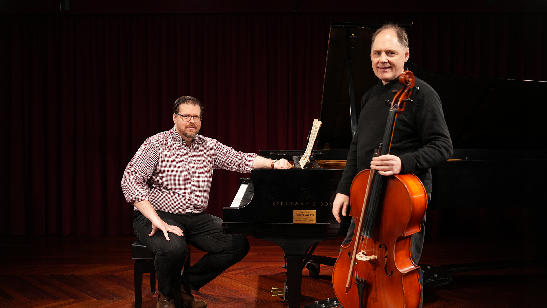 Evan Meier seated at the piano with Vasily Popov holding a cello.