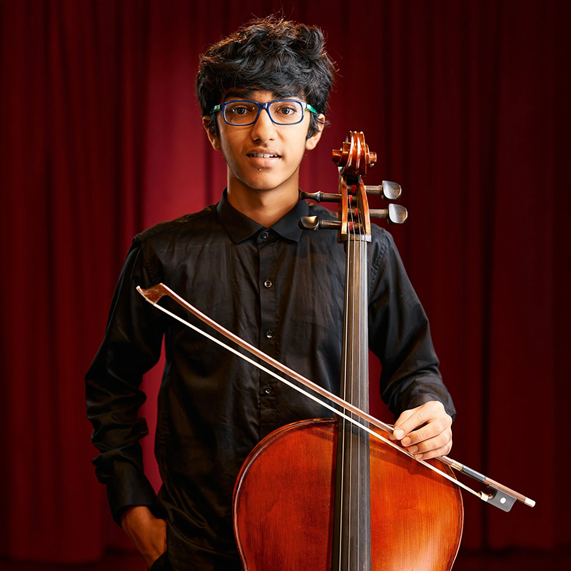 Photo of Ishaan Banerjee holding a cello.