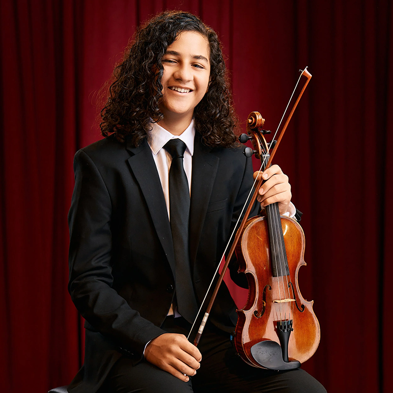 Photo Santiago Funes seated holding a violin.