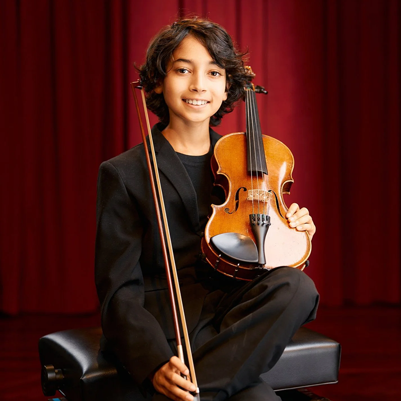 Photo of Siddharth Kravetz seated holding a violin.